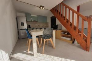 uma cozinha com uma mesa e cadeiras e uma escadaria em Small villa 40m with terrace near the beach em Fleury