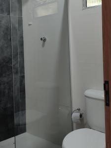 W łazience znajduje się toaleta i przeszklony prysznic. w obiekcie Suíte Maria bonita w mieście Cabo Frio
