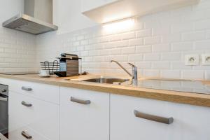 kuchnia z białymi szafkami i zlewem w obiekcie Cosy 40m with terrace in Vannes w mieście Vannes