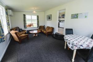 uma sala de estar com cadeiras, uma mesa e um sofá em Cliff Top Cottage 
