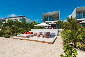 a house on the beach with chairs and an umbrella at Beach Enclave in Providenciales