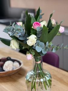 Appartement le penthouse, Villa Les Bains De Mers في مير-لي-بان: مزهرية زجاجية مع الزهور على طاولة