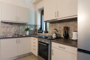 a kitchen with white cabinets and black appliances at Papa-Antonis Stone House in Zaros