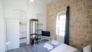 1 Schlafzimmer mit einem Bett, einem TV und einer Ziegelwand in der Unterkunft Mamila space in Jerusalem