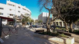 eine Stadtstraße mit einem Baum, Bänken und Gebäuden in der Unterkunft Mamila space in Jerusalem