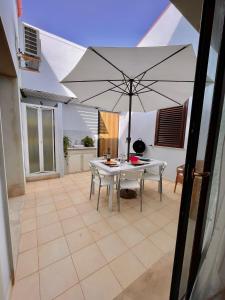 a patio with a white table and an umbrella at Genova La casa di Saretta in Marina di Ragusa