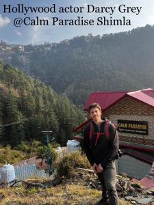 a man standing on the side of a mountain at Calm Paradise in Shimla