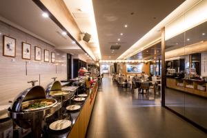 un restaurante con mesas y sillas y una cafetería larga en Chateau-Rich Hotel en Tainan