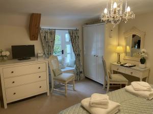 a bedroom with a desk and a bed and a dresser at Millstream Cottage B & B in Dunster