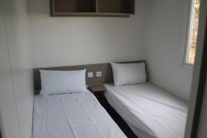 two beds in a room with white walls at mobil home au lac des rêves in Lattes