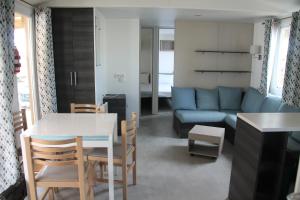 mobil home au lac des rêves في لات: غرفة معيشة مع طاولة وأريكة زرقاء