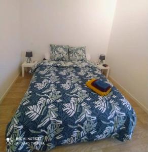 ein Schlafzimmer mit einem Bett mit einer blau-weißen Bettdecke in der Unterkunft Appartement calme in La Montagne