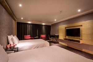 Habitación de hotel con 2 camas y TV de pantalla plana. en Chateau-Rich Hotel en Tainan