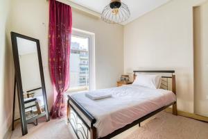 1 dormitorio con cama, espejo y ventana en Escape with Style in this Chic 2BR Apartment!, en Atenas