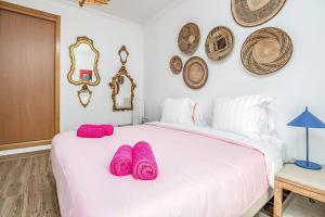 um quarto com uma cama branca com almofadas cor-de-rosa em Casa Sofia no Carvalhal