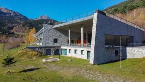 uma casa numa colina com montanhas ao fundo em MónNatura Pirineus - AJOOO385 em Esterri d'Àneu