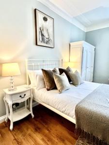 1 dormitorio con cama blanca y mesa con lámpara en Devon House Guest House, en Paignton