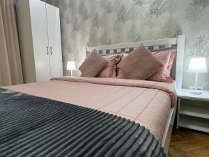 a bedroom with a bed with pink sheets and pillows at Prestige Apartment in Novi Sad