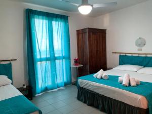 2 camas en una habitación con cortinas azules en La Bussola en Porto Palo
