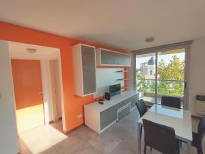 una cocina con una pared de color naranja y una mesa con sillas en Depto Alem en Rosario