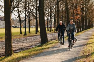 two people riding bikes down a path in a park at De Kasteelhoeve in Westmalle