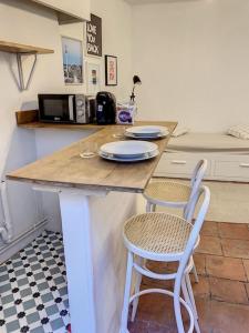 eine Küche mit einer Theke mit 2 Stühlen und einem Tisch in der Unterkunft IBIZA -Sublime studio Place de la Trinité- Netflix in Toulouse