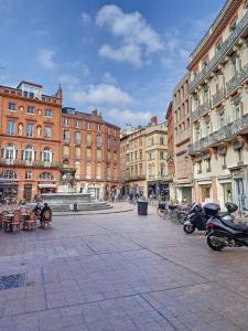 eine Stadtstraße mit Gebäuden und Motorrädern auf der Straße in der Unterkunft IBIZA -Sublime studio Place de la Trinité- Netflix in Toulouse