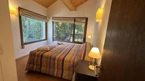 1 dormitorio con 1 cama, 2 ventanas y puerta en Hermoso departamento en el centro de SMA con amplio balcón con parrilla. 35C en San Martín de los Andes