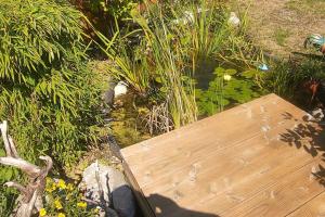 una terraza de madera en un jardín con algunas plantas en Sigrids Ferienwohnung Bad Tölz, en Bad Tölz