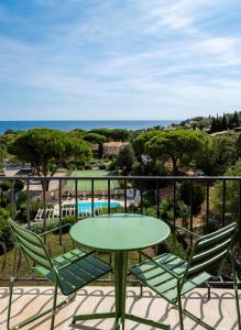 a table and chairs on a balcony with the ocean at Hôtel du Parc Cavalaire sur Mer in Cavalaire-sur-Mer