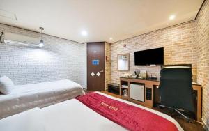 a bedroom with a bed and a desk with a television at Chakan Hotel in Gunsan-si