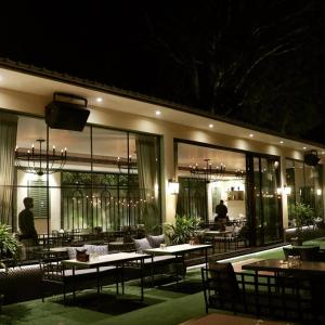 a restaurant with tables and chairs at night at Kingston Resort in Kānpur +41 photos