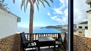 a table and chairs on a balcony with a view of the ocean at DELUXE SeaView-SUNSETS !TRANSFE-R inc! POOL,2AirCond,2TV65",600Mb Dishwasher,,2 BEACHes,ANFI-view in Patalavaca