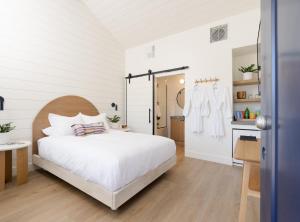 a bedroom with a white bed and a bathroom at The Pacific Motel in Cayucos