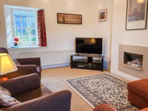 a living room with a tv and a couch and a fireplace at Quay Cottage in Cramond