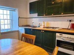 a kitchen with green cabinets and a wooden table at Quay Cottage in Cramond