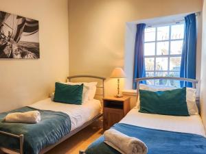 a bedroom with two beds and a window at Quay Cottage in Cramond
