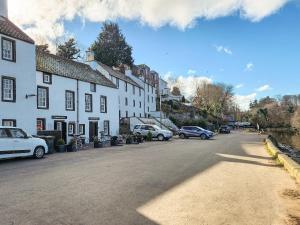 a street in a town with cars parked on the road at Quay Cottage in Cramond