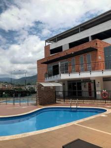 a building with a swimming pool in front of a building at Hospedaje Los Cedros in Girón