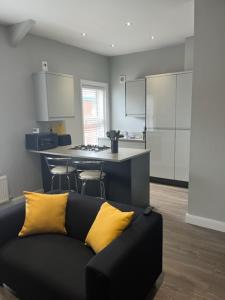 a black couch with yellow pillows in a kitchen at Stanley Street Apartment in Southport