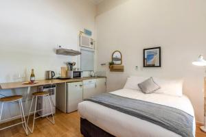 een kleine slaapkamer met een bed en een keuken bij Gawler Townhouses 1 Bedroom (1c) in Gawler