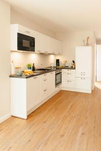 a kitchen with white cabinets and a wooden floor at Utkiek Stuuv in Ratzeburg