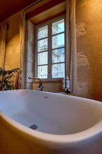 La salle de bains est pourvue d'une baignoire blanche et d'une fenêtre. dans l'établissement La Chapelle, Les Suites du Palais, l'unique 5 étoiles de Nevers, Suite d'Exception, by PRIMO C0NCIERGERIE, à Nevers