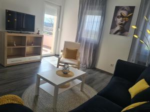 ein Wohnzimmer mit einem Sofa, einem Tisch und einem TV in der Unterkunft Apartman Lea in Kraljevec Sesvetski