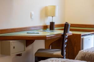 einen Schreibtisch in einem Zimmer mit einem Bett und einem Stuhl in der Unterkunft Hotel Bella Italia in Foz do Iguaçu