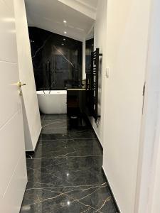 een badkamer met een bad en een zwarte tegelvloer bij Bel Appartement avec parking au coeur de Reims in Reims