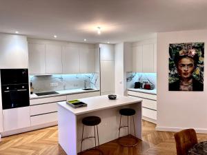 een keuken met witte kasten en een aanrecht met krukken bij Bel Appartement avec parking au coeur de Reims in Reims