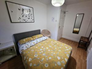 een slaapkamer met een bed met een geel dekbed bij City Budget Guesthouse in Londen