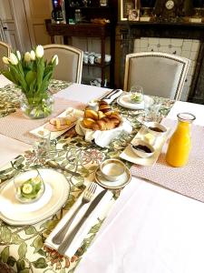 a table with plates and utensils and bread on it at Le Manoir des Doyens in Bayeux