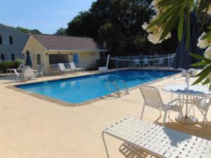 a swimming pool with chairs and a table and a table and chairs at E10 comfortable and neat 2 bedroom 2 bath in Saint Simons Island
